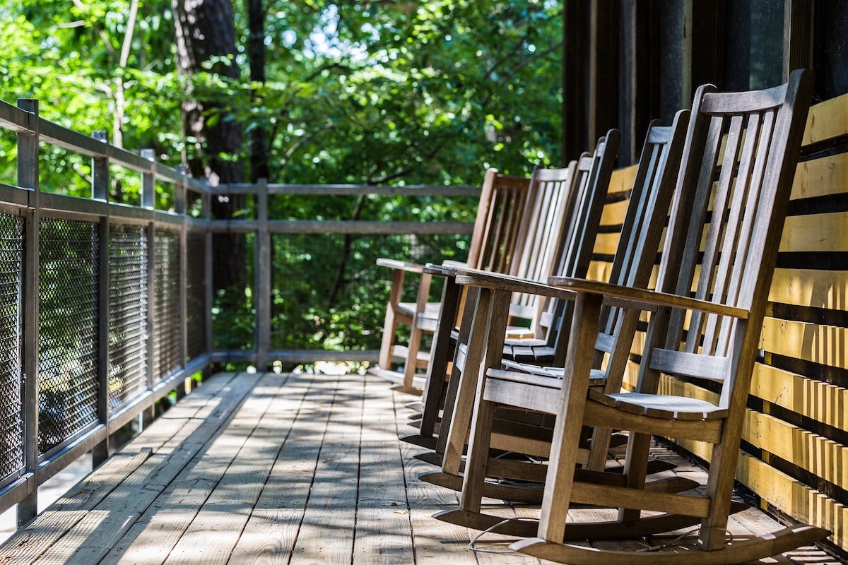 Wooden porch with half height screening fence with rocking chairs in a row